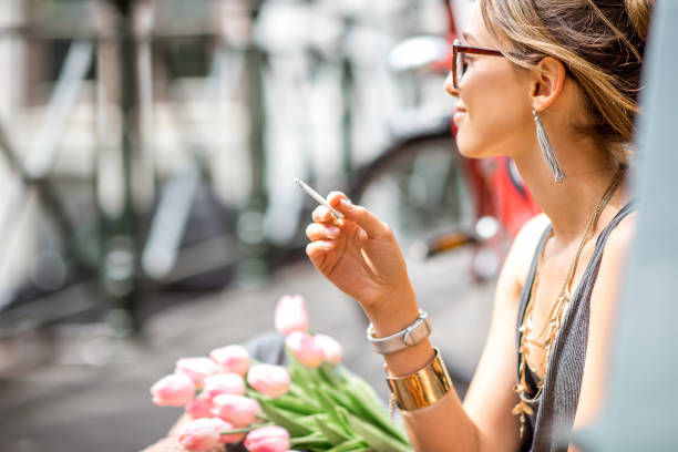 Young beautiful woman smoking a cigarette sitting with flowers in Amsterdam city